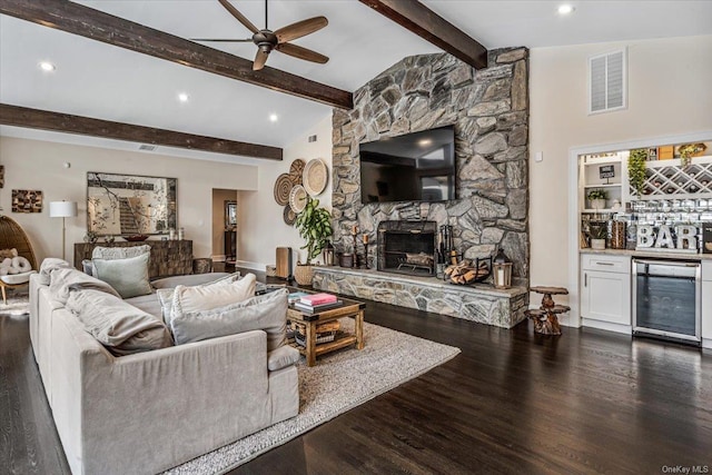 living room with beverage cooler, dark wood-type flooring, ceiling fan, indoor bar, and a stone fireplace