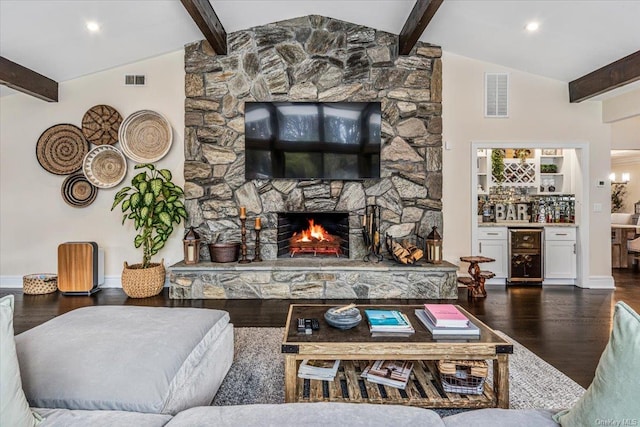 living room with lofted ceiling with beams, a stone fireplace, indoor bar, dark hardwood / wood-style floors, and beverage cooler