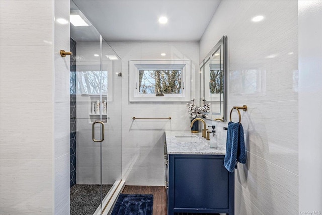 bathroom featuring hardwood / wood-style floors, vanity, an enclosed shower, and tile walls