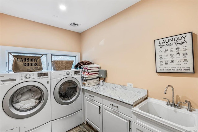 washroom featuring washing machine and dryer, sink, and cabinets