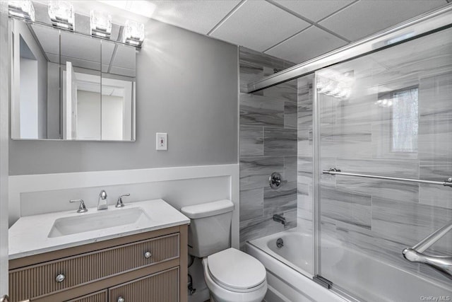 full bathroom with a paneled ceiling, vanity, toilet, and shower / bath combination with glass door