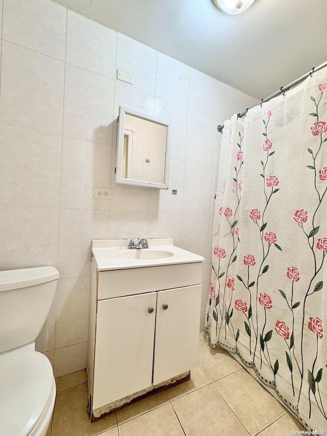 bathroom featuring a shower with shower curtain, tile patterned floors, vanity, tile walls, and toilet