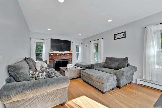 living room with a fireplace, a healthy amount of sunlight, and light wood-type flooring