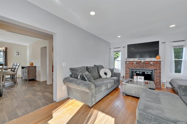 living room with a fireplace, plenty of natural light, hardwood / wood-style floors, and an inviting chandelier