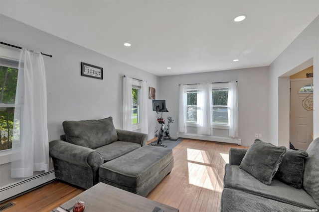 living room with light hardwood / wood-style floors, plenty of natural light, and a baseboard heating unit