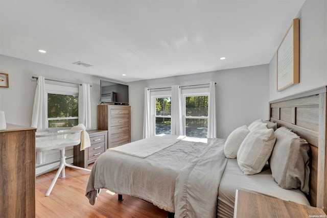 bedroom featuring baseboard heating and light hardwood / wood-style floors