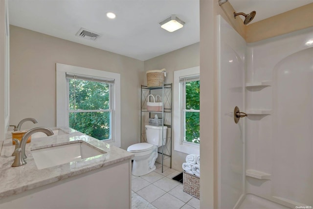 bathroom featuring toilet, vanity, tile patterned floors, and a wealth of natural light