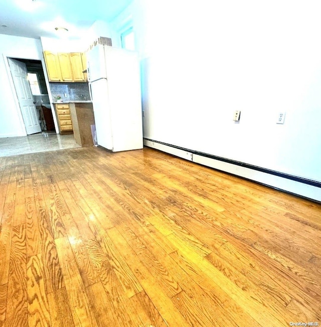 kitchen with decorative backsplash, light wood-type flooring, white refrigerator, and light brown cabinets