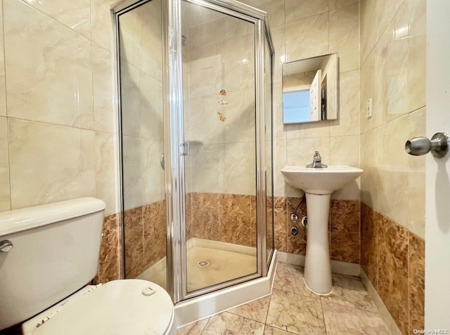 bathroom with sink, toilet, tile walls, and walk in shower