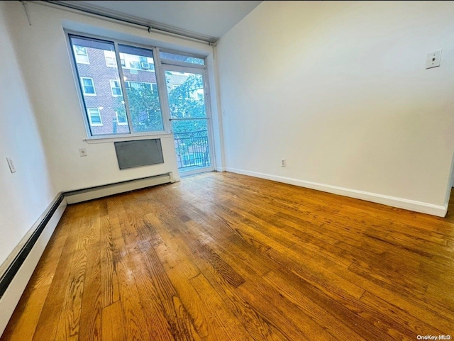 unfurnished room with wood-type flooring and baseboard heating