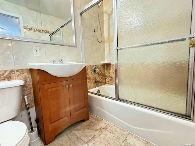 full bathroom featuring toilet, vanity, tile walls, and combined bath / shower with glass door