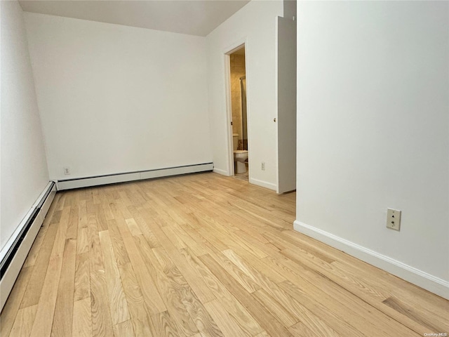 empty room with a baseboard radiator and light hardwood / wood-style flooring