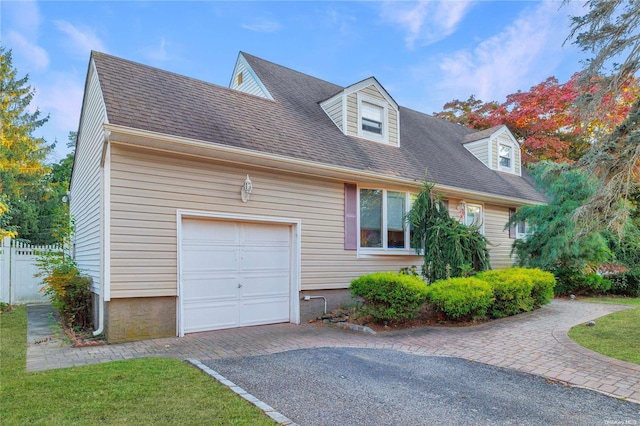 new england style home with a garage, driveway, fence, and a shingled roof