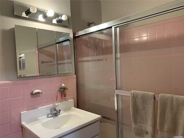 bathroom with decorative backsplash, vanity, a shower with door, and tile walls