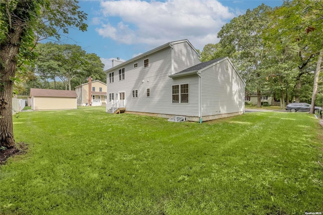 rear view of house featuring a lawn and an outbuilding