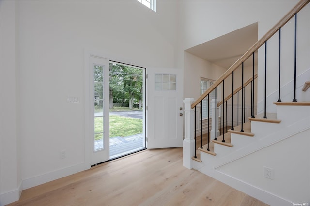 foyer entrance featuring a high ceiling, light hardwood / wood-style floors, and plenty of natural light