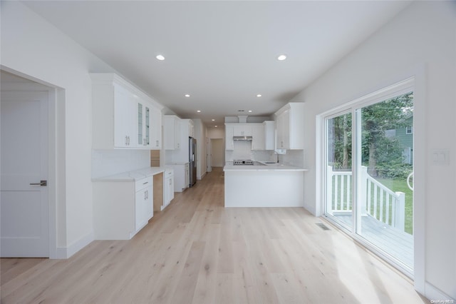 kitchen with white cabinets, decorative backsplash, and light wood-type flooring