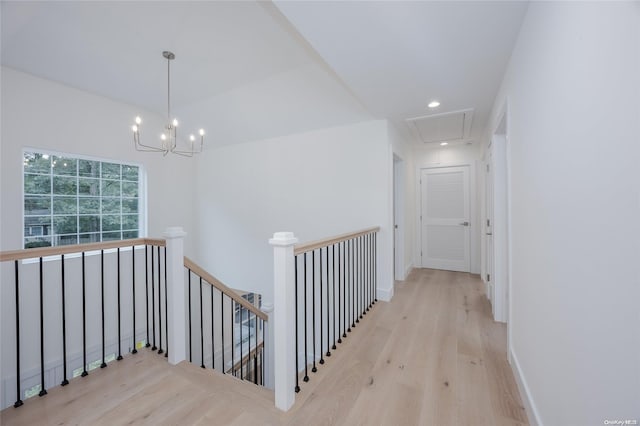 hallway with light hardwood / wood-style floors and an inviting chandelier