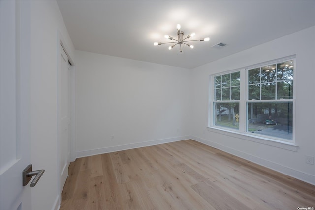 unfurnished room with light hardwood / wood-style flooring and a chandelier