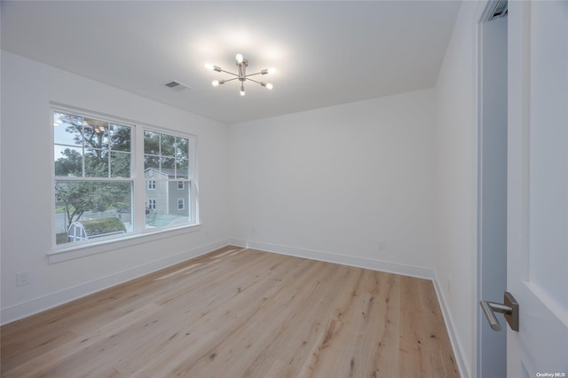 unfurnished room featuring light hardwood / wood-style floors and a notable chandelier