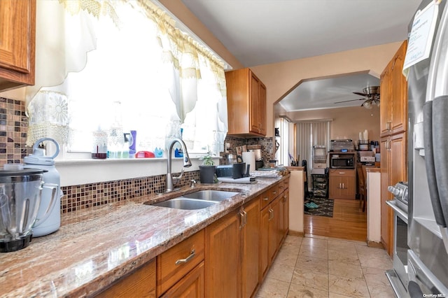 kitchen with decorative backsplash, light stone counters, and sink