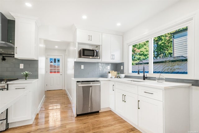 kitchen with appliances with stainless steel finishes, light hardwood / wood-style flooring, white cabinetry, and plenty of natural light