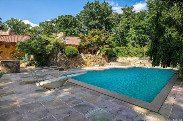 view of swimming pool featuring a diving board and a patio area