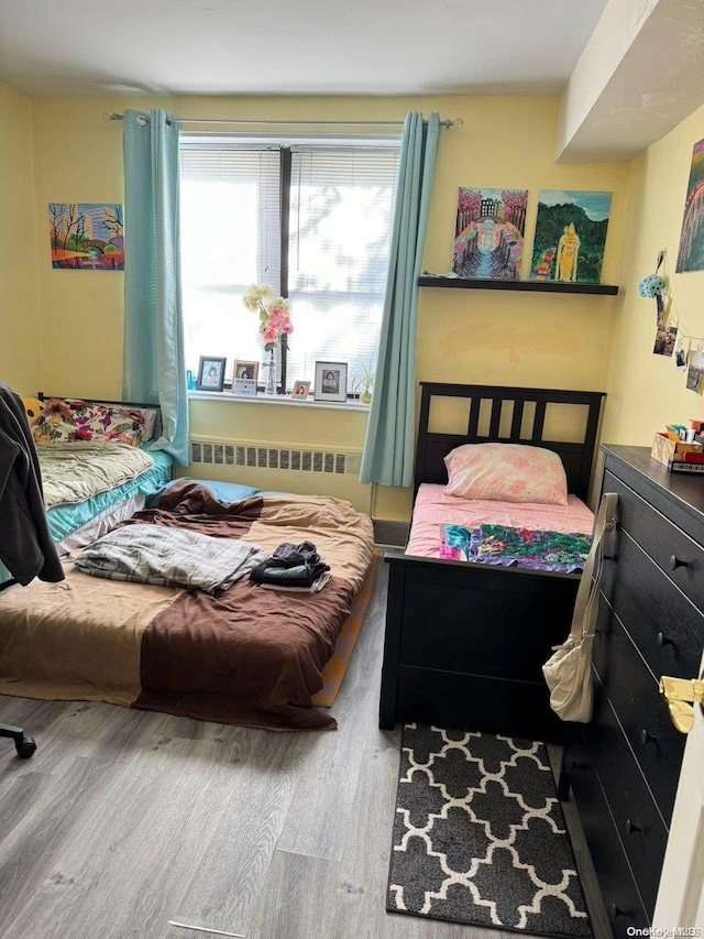 bedroom featuring radiator heating unit and hardwood / wood-style floors