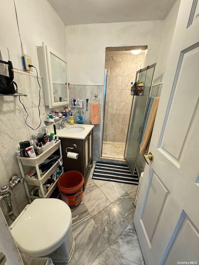 bathroom with vanity, an enclosed shower, tile walls, and toilet