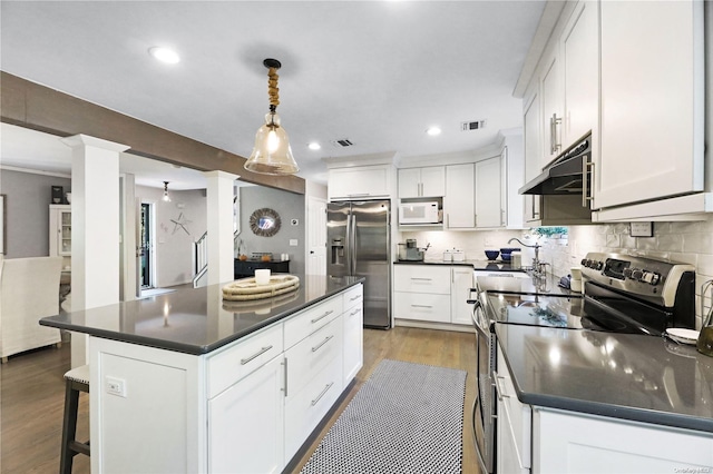 kitchen featuring a center island, hardwood / wood-style flooring, appliances with stainless steel finishes, decorative light fixtures, and white cabinetry