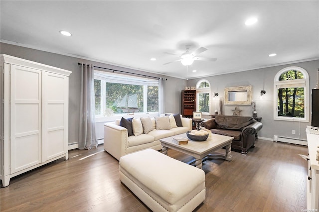 living room featuring dark hardwood / wood-style flooring, baseboard heating, crown molding, and ceiling fan