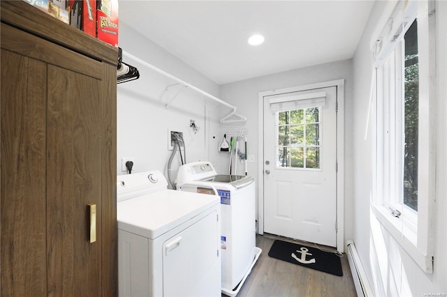 laundry area featuring hardwood / wood-style floors, baseboard heating, and washing machine and clothes dryer