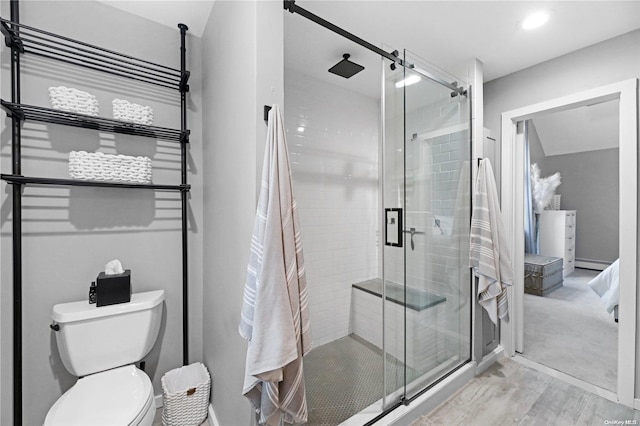 bathroom with hardwood / wood-style flooring, toilet, baseboard heating, and a shower with shower door