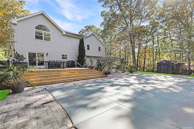 rear view of property featuring a deck and a storage shed