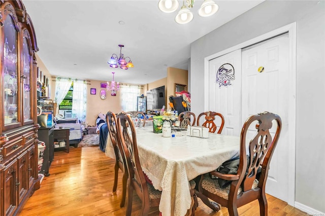 dining area with light wood-type flooring and a notable chandelier