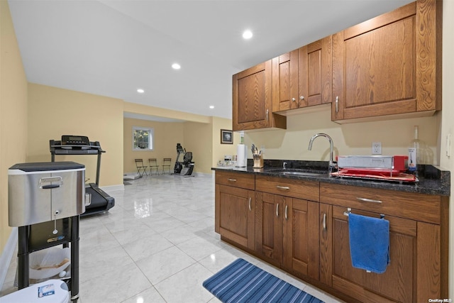 kitchen featuring light tile patterned flooring, dark stone counters, and sink