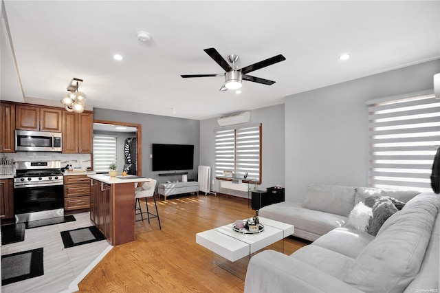 living room with ceiling fan, light hardwood / wood-style floors, and a wall unit AC