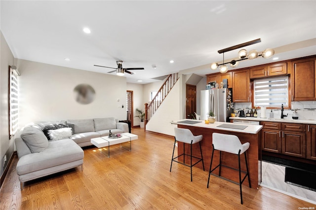 kitchen featuring a kitchen breakfast bar, tasteful backsplash, light hardwood / wood-style flooring, a center island, and stainless steel refrigerator