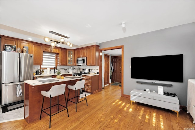 kitchen featuring a kitchen breakfast bar, stainless steel appliances, decorative light fixtures, light hardwood / wood-style flooring, and a kitchen island