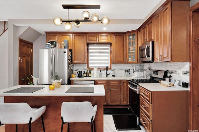 kitchen featuring a kitchen breakfast bar, sink, tasteful backsplash, decorative light fixtures, and stainless steel appliances