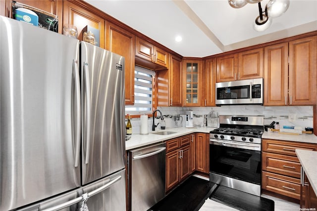 kitchen with decorative backsplash, light stone counters, sink, and appliances with stainless steel finishes