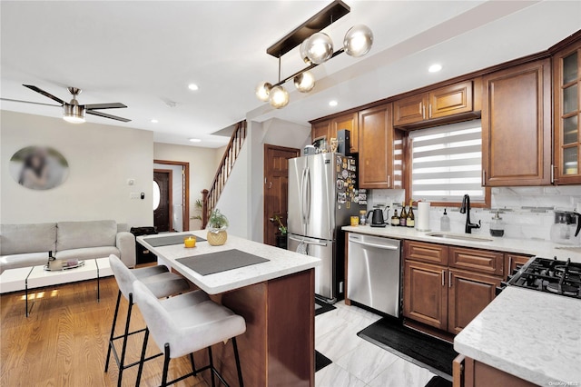 kitchen featuring backsplash, sink, light hardwood / wood-style floors, appliances with stainless steel finishes, and a kitchen island