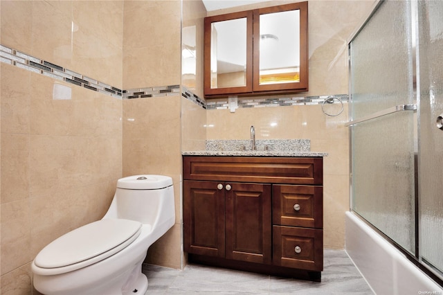 full bathroom with vanity, toilet, enclosed tub / shower combo, and tile walls