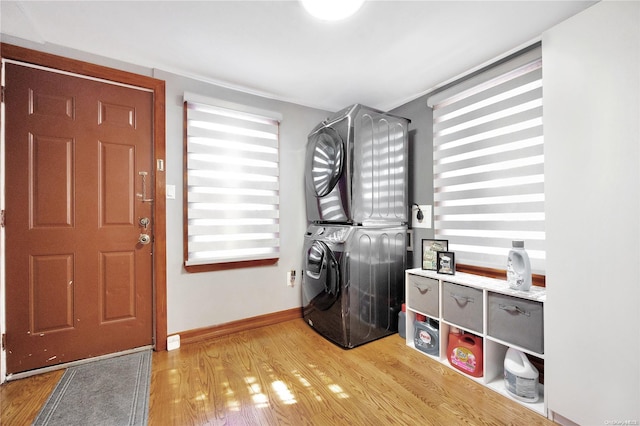 clothes washing area featuring light hardwood / wood-style floors and stacked washing maching and dryer