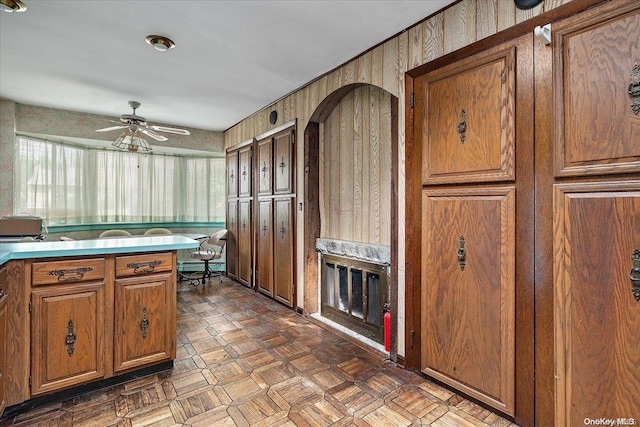 kitchen with dark parquet flooring, ceiling fan, and wooden walls