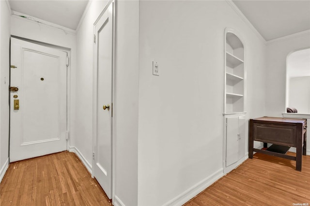 corridor featuring ornamental molding, built in features, and light hardwood / wood-style floors