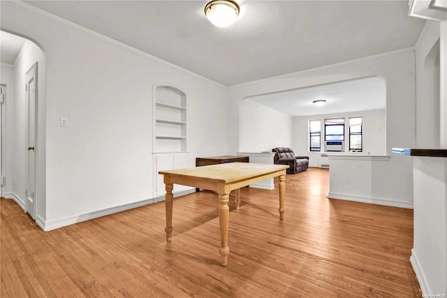 dining area with crown molding, light wood-type flooring, and built in shelves