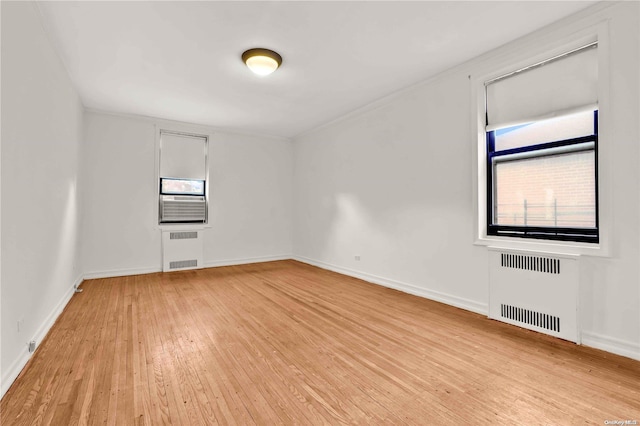 unfurnished room featuring radiator and light hardwood / wood-style flooring