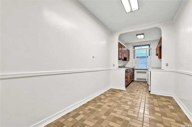 kitchen with crown molding, radiator heating unit, sink, and white fridge