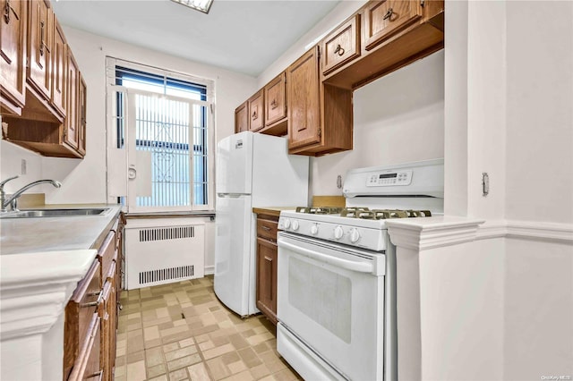 kitchen featuring radiator, white appliances, and sink